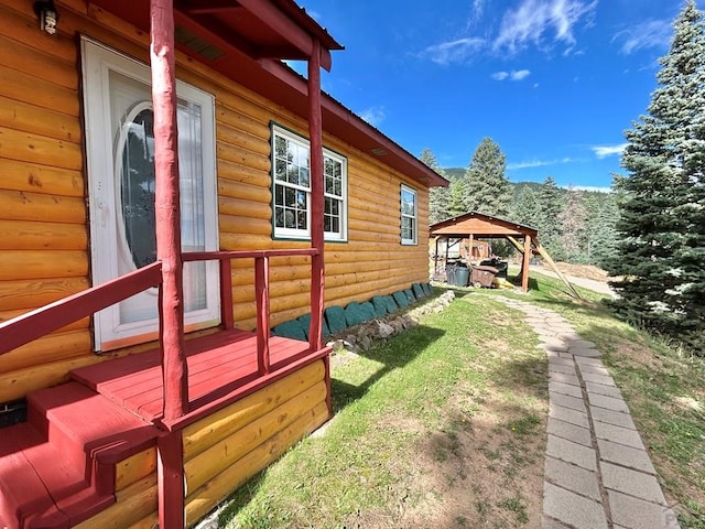 view of side of home with faux log siding and a gazebo