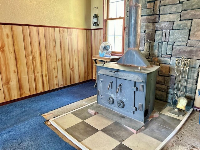 room details with a textured wall, wood walls, carpet, and a wood stove