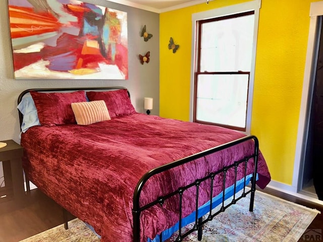 bedroom featuring crown molding, baseboards, and wood finished floors