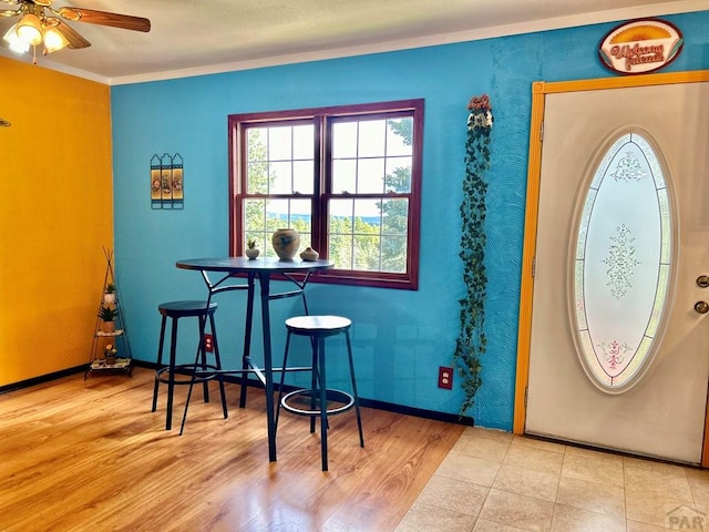 entrance foyer with ornamental molding, light wood-type flooring, ceiling fan, and baseboards