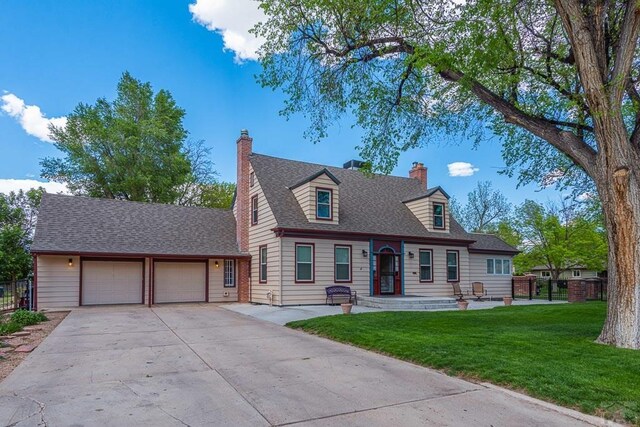 cape cod house with a shingled roof, concrete driveway, a chimney, an attached garage, and a front lawn