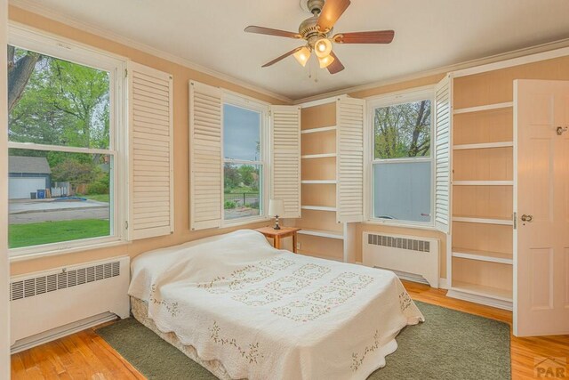 bedroom with ornamental molding, radiator heating unit, wood finished floors, and a ceiling fan