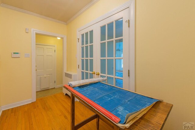 interior space with french doors, radiator heating unit, ornamental molding, wood finished floors, and baseboards