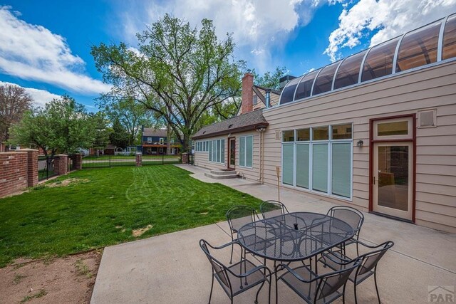 view of patio with entry steps, outdoor dining space, fence, and a sunroom