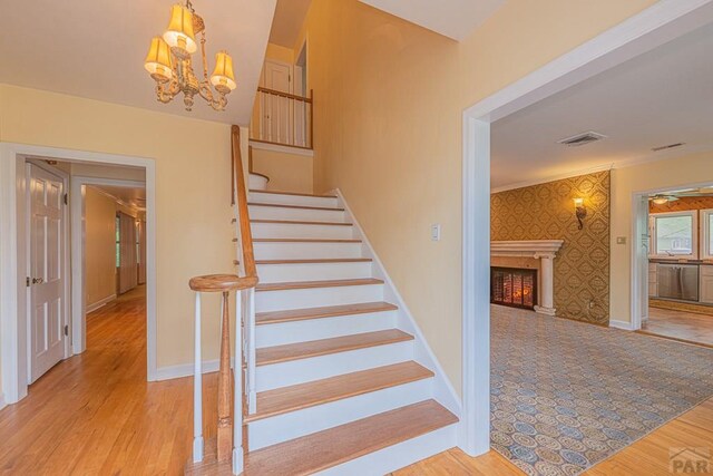 staircase with an accent wall, wood finished floors, baseboards, and wallpapered walls