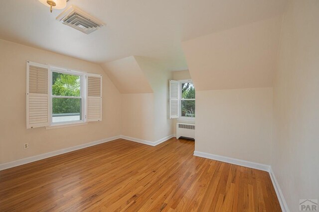 additional living space featuring radiator, visible vents, light wood finished floors, and baseboards