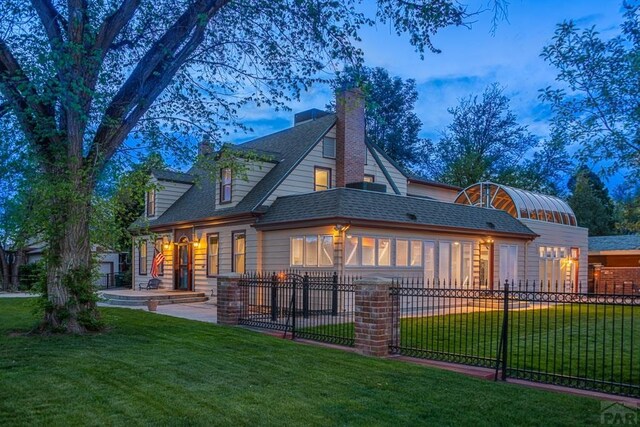 rear view of house with roof with shingles, fence, and a yard