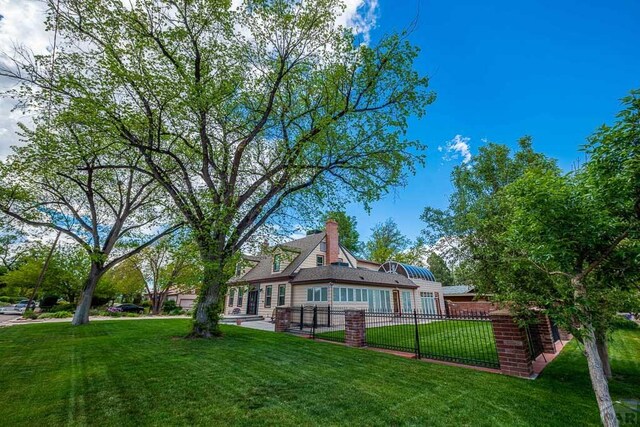 back of house with a lawn, a chimney, and fence