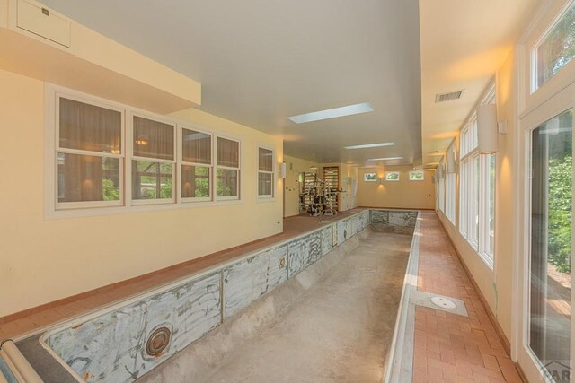 corridor featuring brick floor, a skylight, and visible vents