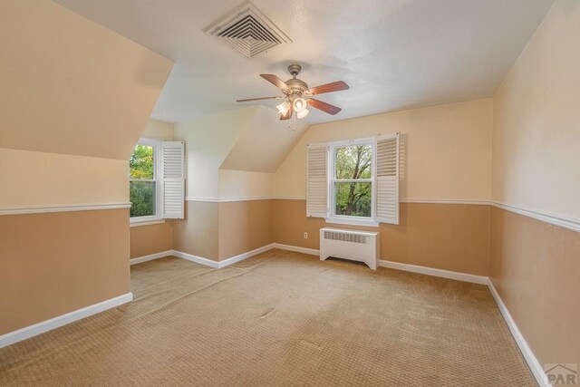 bonus room with radiator heating unit, visible vents, vaulted ceiling, and light colored carpet