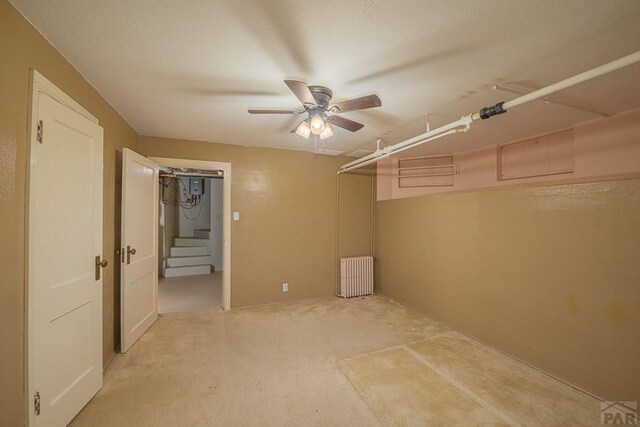 interior space featuring a ceiling fan, radiator, and light carpet