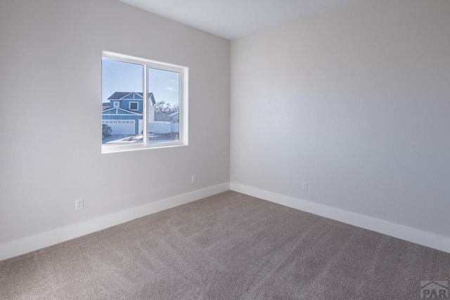 carpeted spare room featuring baseboards