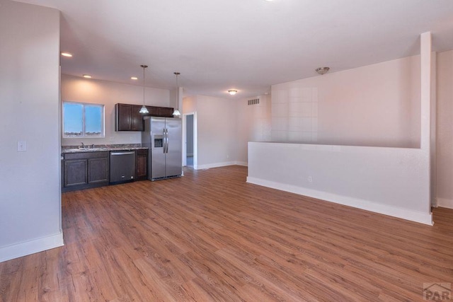 kitchen with visible vents, open floor plan, wood finished floors, stainless steel fridge, and dishwasher