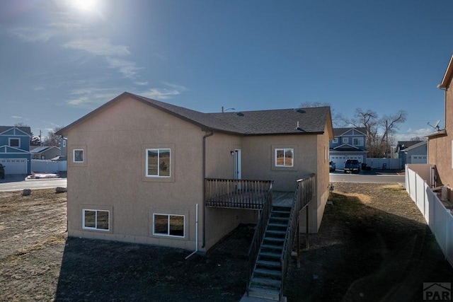 rear view of property with a residential view, fence, stairway, and stucco siding