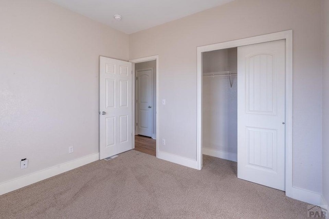 unfurnished bedroom featuring carpet floors, visible vents, baseboards, and a closet