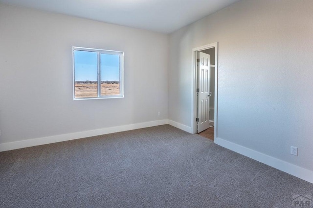 unfurnished room with dark carpet and baseboards