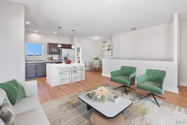 living area with light wood-style floors, baseboards, visible vents, and recessed lighting