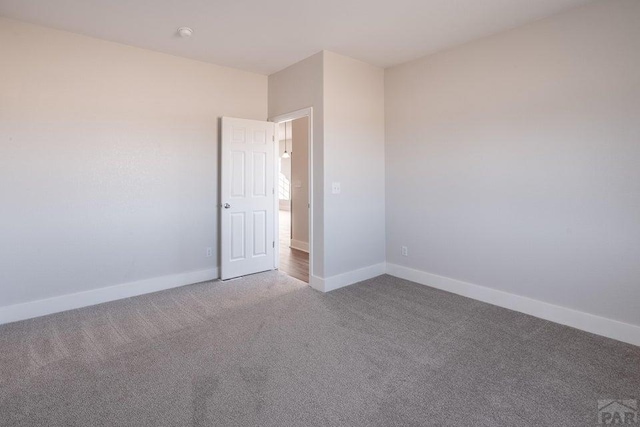 empty room featuring carpet floors and baseboards