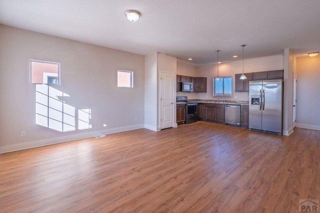 kitchen with stainless steel appliances, light wood finished floors, hanging light fixtures, and baseboards