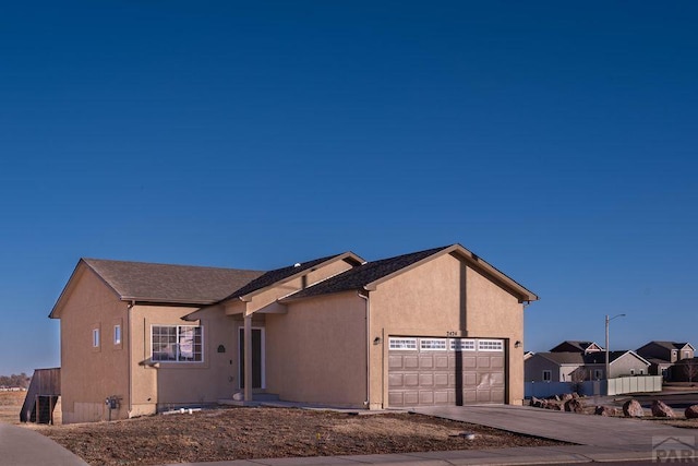 view of front facade featuring concrete driveway, an attached garage, and stucco siding