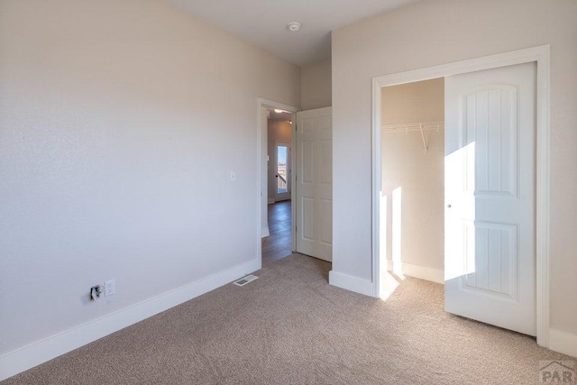 unfurnished bedroom featuring light carpet, baseboards, visible vents, and a closet