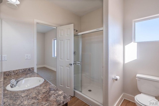 bathroom with a stall shower, a healthy amount of sunlight, and toilet