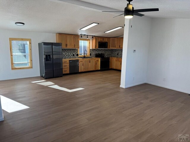 kitchen featuring decorative backsplash, dark wood-type flooring, open floor plan, a sink, and black appliances