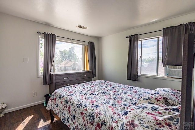 bedroom with multiple windows, dark wood finished floors, visible vents, and baseboards