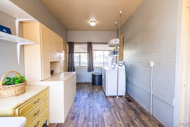 laundry room with brick wall, washing machine and dryer, laundry area, and dark wood-type flooring