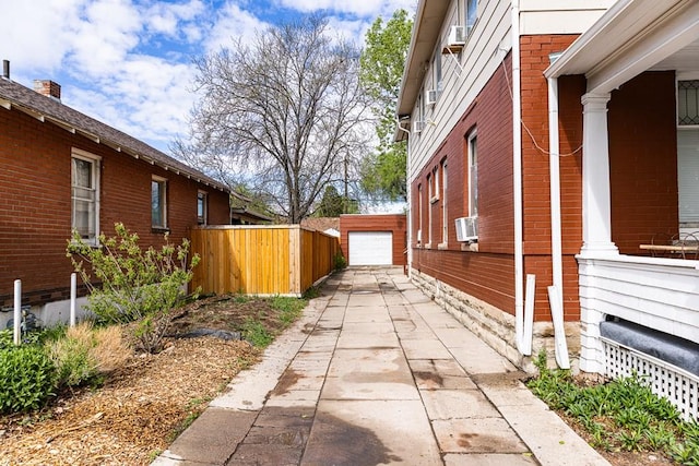 view of home's exterior featuring a garage, fence, cooling unit, an outdoor structure, and brick siding