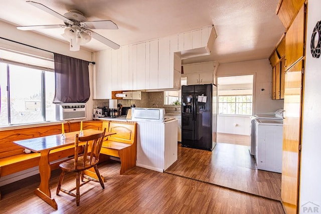 kitchen featuring light wood-style flooring, black refrigerator with ice dispenser, cooling unit, light countertops, and separate washer and dryer