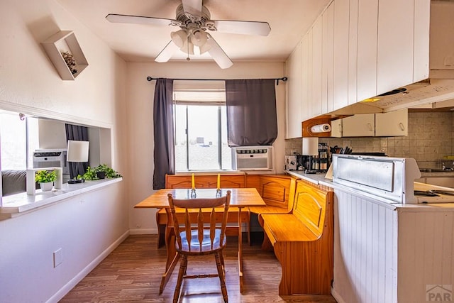 kitchen with tasteful backsplash, breakfast area, wood finished floors, light countertops, and cooling unit