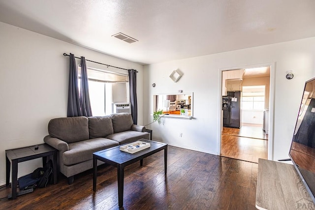 living room with dark wood-style floors, plenty of natural light, visible vents, and baseboards