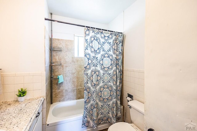 full bath featuring toilet, shower / tub combo, vanity, tile walls, and wainscoting