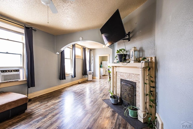 living room with cooling unit, a fireplace with flush hearth, baseboards, and wood finished floors