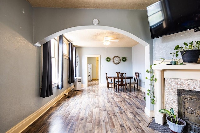 interior space featuring arched walkways, a textured ceiling, and wood finished floors