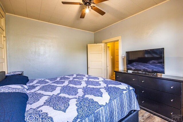 bedroom featuring ceiling fan, crown molding, and wood finished floors