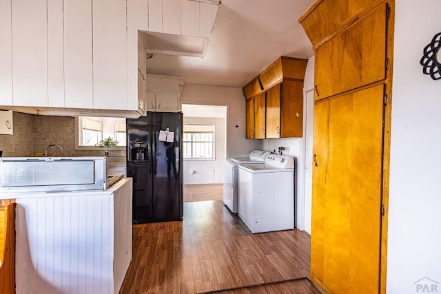 kitchen with dark wood-style floors, washing machine and dryer, light countertops, and black fridge