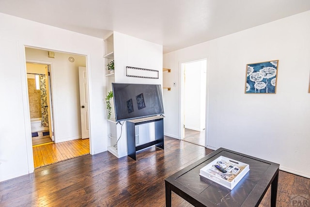 living area featuring baseboards and dark wood-type flooring