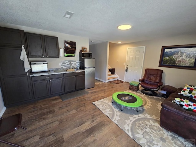 kitchen featuring stainless steel appliances, dark wood-type flooring, visible vents, and a textured ceiling