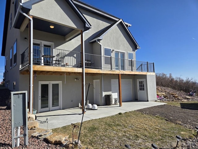 rear view of house featuring an attached garage, a patio area, and stucco siding