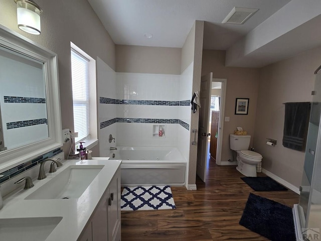 full bath featuring visible vents, toilet, a tub, wood finished floors, and vanity