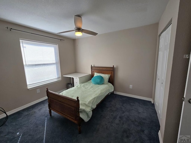 bedroom featuring dark carpet, a textured ceiling, baseboards, and ceiling fan