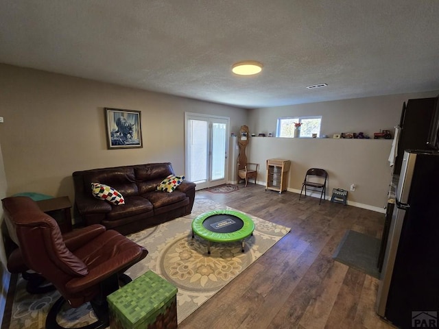 living area with visible vents, a textured ceiling, dark wood-type flooring, and baseboards