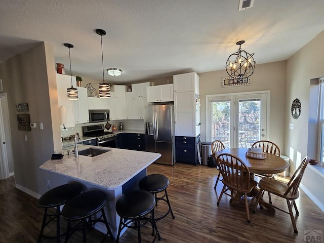 kitchen featuring a sink, appliances with stainless steel finishes, a peninsula, white cabinetry, and dark wood-style flooring