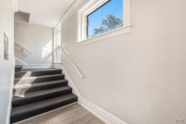 staircase featuring visible vents, baseboards, and wood finished floors