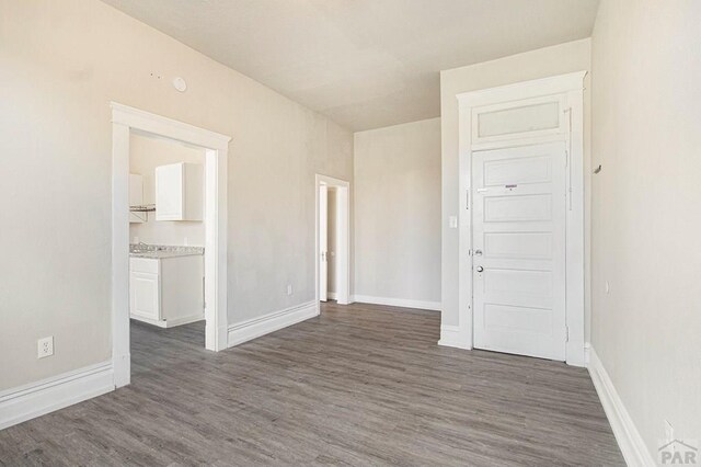 empty room featuring dark wood-type flooring and baseboards