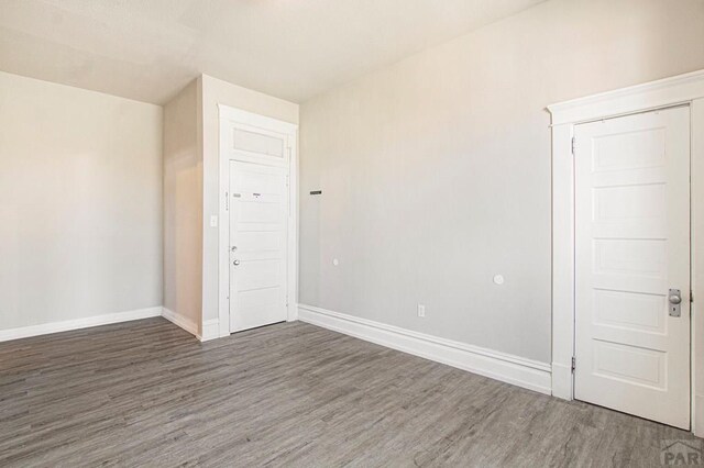 empty room with dark wood-style flooring and baseboards