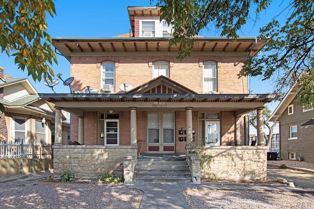 italianate home featuring a porch and brick siding