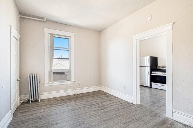 empty room featuring radiator, baseboards, and wood finished floors